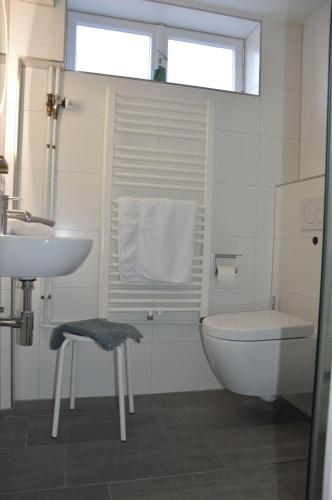 a white bathroom with a toilet and a sink at Reethaus-am-Strand in Südstrand