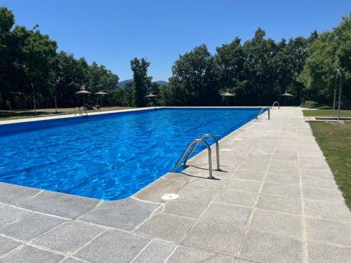 a large swimming pool with blue water at Casa Mama Puchi in Cercedilla