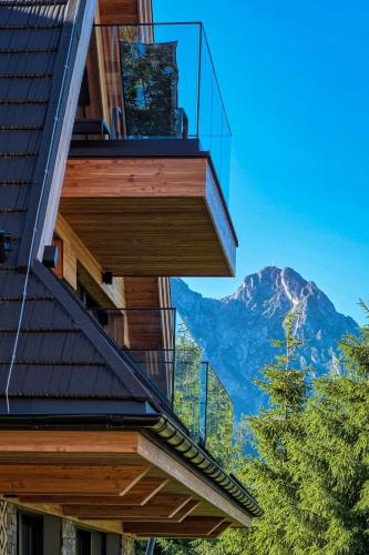 a house with a balcony with a mountain in the background at Apartamenty 3 Owce z widokiem na Giewont in Kościelisko