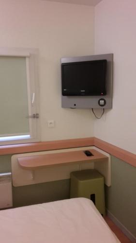 a bedroom with a tv on the wall and a desk at ibis budget Orly Rungis in Rungis