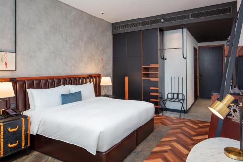 a bedroom with a large white bed and a table at DoubleTree by Hilton Dubai M Square Hotel & Residences in Dubai