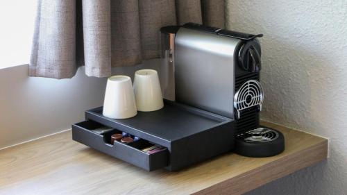 a black hair dryer sitting on a shelf with towels at Campanile Prime - Argenteuil in Argenteuil