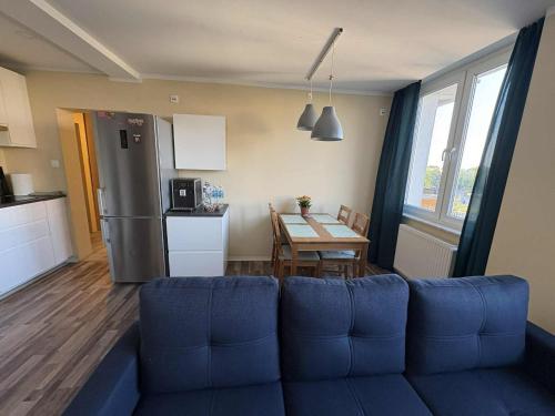 a living room with a blue couch and a kitchen at Apartament Bazyliańska, metro Bródno in Warsaw