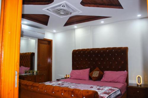 a bedroom with a bed with purple pillows and a mirror at Umair's Haven Residences, Luxury Apartments in Bahria Town Lahore in Lahore