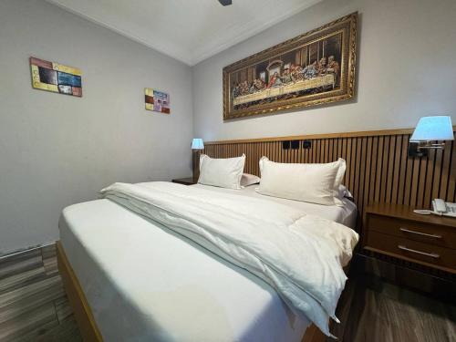 a bedroom with a large bed and a painting on the wall at Bayview in Accra