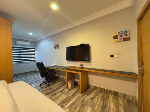 a room with a desk with a tv on a wall at Bayview in Accra