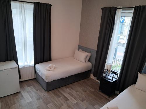 a small bedroom with a bed and two windows at Saint Annes Guest House - 22 Berkeley in Dublin