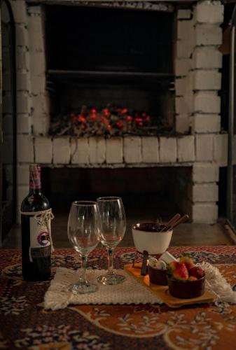 a table with two wine glasses and a bottle of wine at ChaletElMuisca RaicesQueAcogen in Nemocón