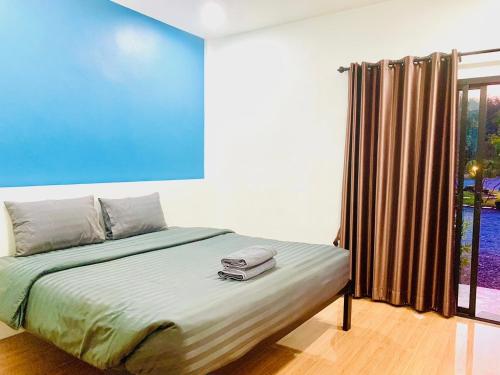 a bedroom with a bed with a blue wall at Suanvadee Resort สวนวดี รีสอร์ท in Don Sak