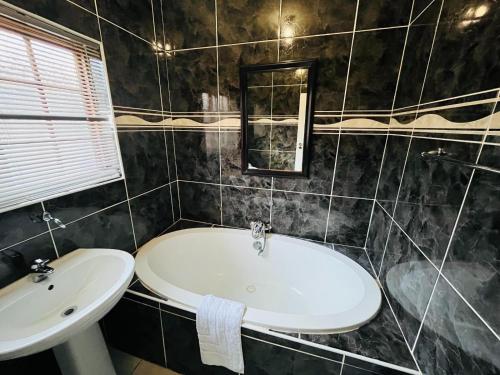 a bathroom with a sink and a bath tub at Leruo's Guest House in Kimberley