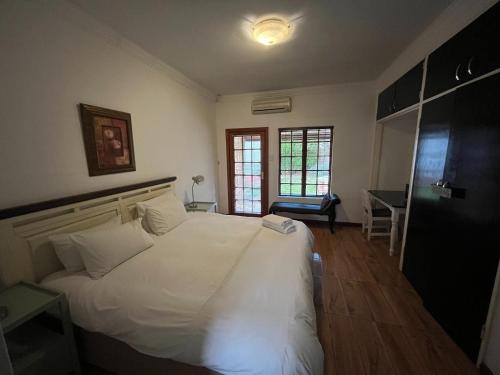 a bedroom with a large white bed and a desk at Leruo's Guest House in Kimberley