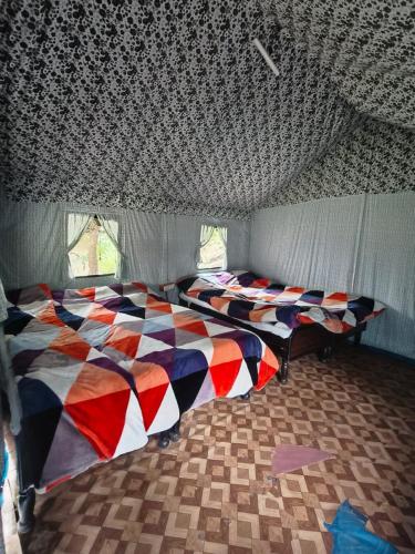 a bedroom with two beds in a room with a ceiling at Namaste Sari in Chopta
