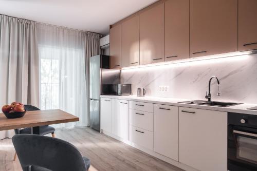 a kitchen with white cabinets and a wooden table at Symphony City Square Aparthotel in Wrocław