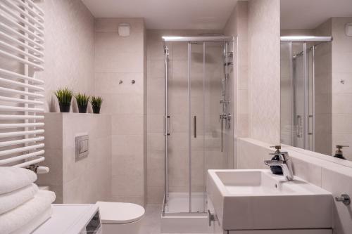 a white bathroom with a shower and a sink at Symphony City Square Aparthotel in Wrocław