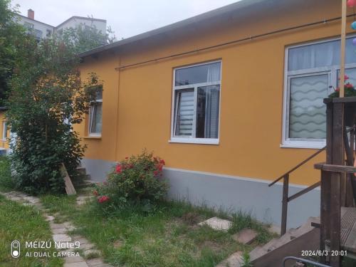 a yellow house with two windows and a yard at Appartement mit Garten zentrumnah in Schwerin