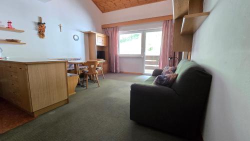 a living room with a couch and a kitchen with a table at Appartamenti Bernard Sas in Canazei