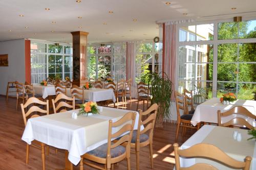 un ristorante con tavoli e sedie bianchi e finestre di Hotel St Hubertus Wienrode a Wienrode