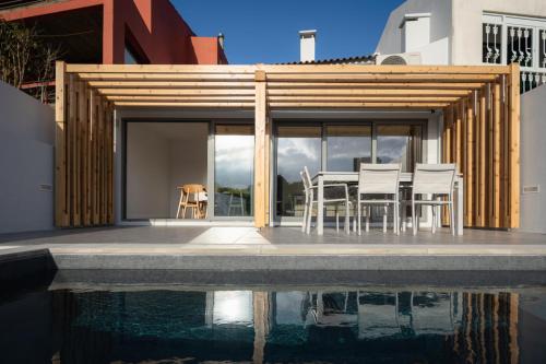 a house with a table and chairs next to a pool at Figueiras House Pópulo Beach in Ponta Delgada