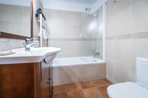 a bathroom with a sink and a tub and a toilet at Apartamentos Casa Pichuana in Benasque