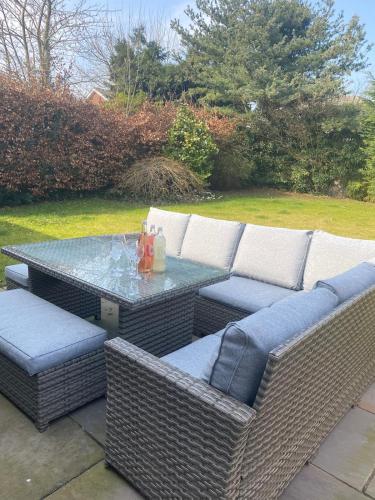 a patio with a table and wicker chairs and a table and chairs at York - Entire Holiday Home with parking and garden in Nether Poppleton
