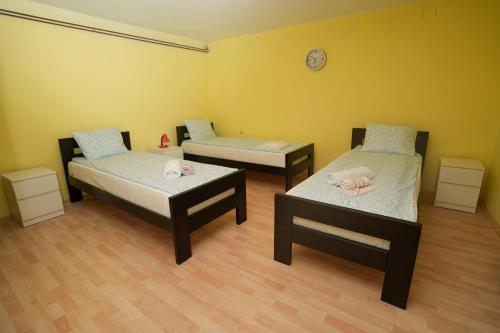 a room with two beds and a clock on the wall at ROLA - smeštaj in Paraćin