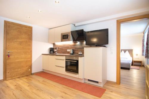 a room with a kitchen with a television and a door at Haus Partoll in Kappl