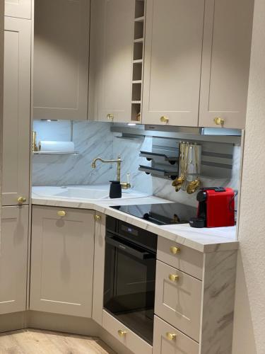 a kitchen with white cabinets and a red appliance at Modernes Apartment an Timmendorfer Promenade, 1. Reihe in Timmendorfer Strand
