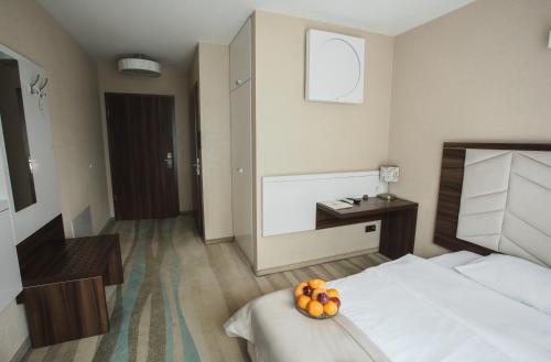 a hotel room with a bed with a bowl of oranges on it at Hotel Pogoria Residence in Dąbrowa Górnicza