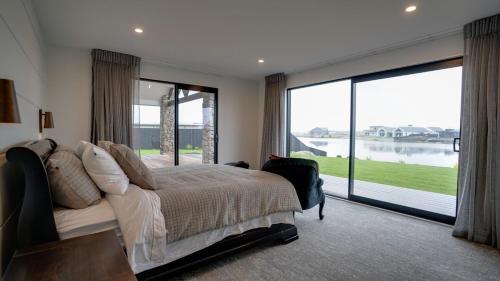 a bedroom with a large bed and a large window at Lake Hood Escape & Private Jetty in Ashburton