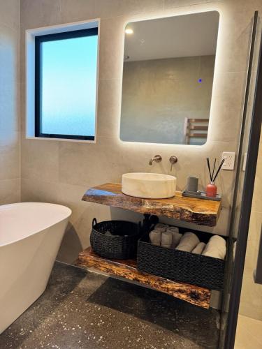 a bathroom with a sink and a mirror and a tub at Lake Hood Escape & Private Jetty in Ashburton