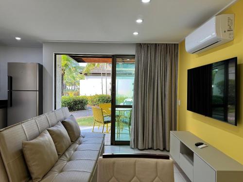a living room with a couch and a television at Flat ou Bangalo Luxo Beach Class Beira Mar Muro Alto in Porto De Galinhas