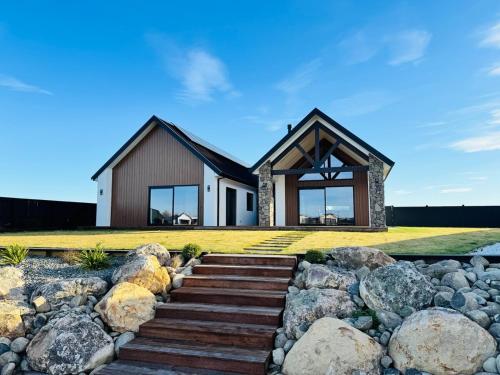 a house with rocks in front of it at Lake Hood Escape & Private Jetty in Ashburton