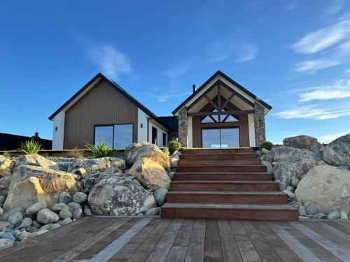 a house on the beach with rocks and stairs at Lake Hood Escape & Private Jetty in Ashburton