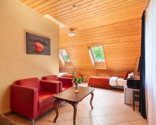 a living room with red chairs and a table and a bedroom at Slėnis Trakuose in Trakai