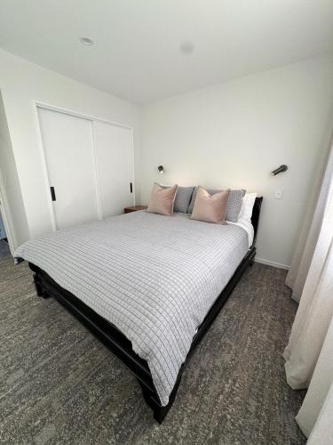 a bedroom with a large bed with pink pillows at Lake Hood Escape & Private Jetty in Ashburton