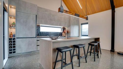 a kitchen with a counter and stools at a bar at Lake Hood Escape & Private Jetty in Ashburton