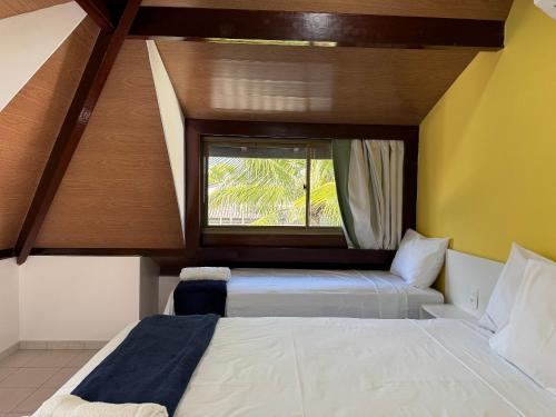 two beds in a room with a window at Flat ou Bangalo Luxo Beach Class Beira Mar Muro Alto in Porto De Galinhas