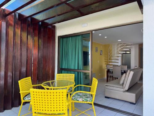 a patio with yellow chairs and a table and a couch at Flat ou Bangalo Luxo Beach Class Beira Mar Muro Alto in Porto De Galinhas