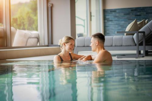 a man and woman sitting in a swimming pool at Königswieser Hof in Königswiesen