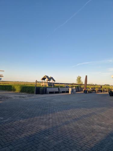 a park with a bench and a bridge in the background at B&B De Veldmuis in Eemdijk
