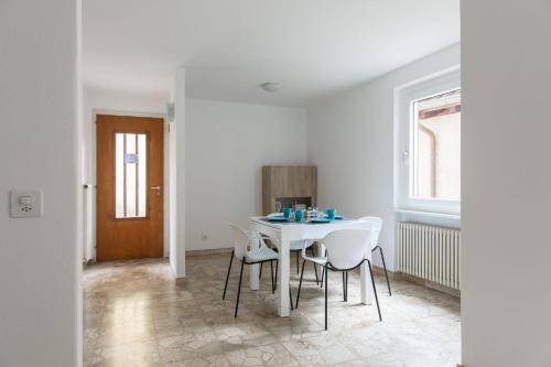 a white dining room with a table and chairs at Rose 2 Apartment by Quokka 360 - duplex on 2 floors with balcony in Ruvigliana