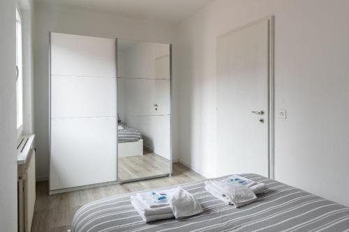 a white bedroom with a bed and a mirror at Rose 2 Apartment by Quokka 360 - duplex on 2 floors with balcony in Ruvigliana