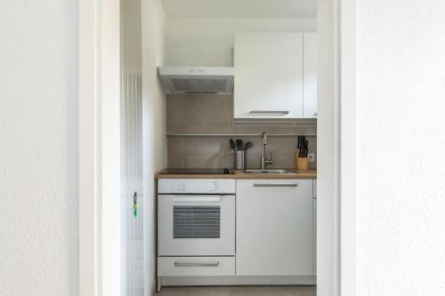 a kitchen with white cabinets and a sink at Rose 2 Apartment by Quokka 360 - duplex on 2 floors with balcony in Ruvigliana