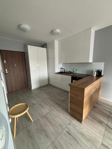 a kitchen with white cabinets and a table and a chair at Urocza i nowoczesna kawalerka - Łódź w pobliżu centrum in Łódź