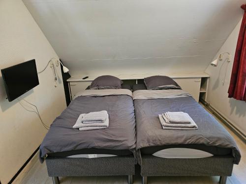 a small bedroom with two beds with towels on them at Bungalow het Zuiderveld in Geesbrug