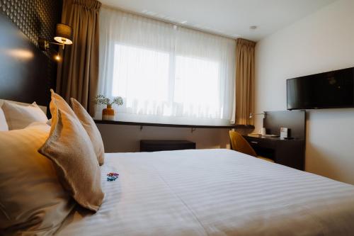 a hotel room with a large bed with a window at Clarion Aparthotel Toulouse Le Parc de l'Escale in Toulouse