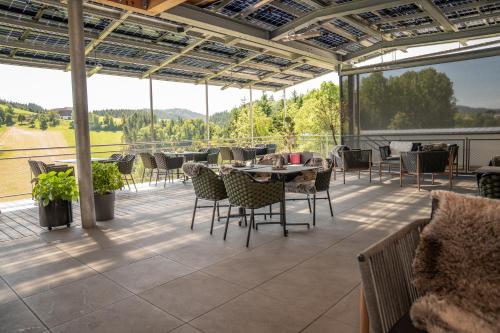 a patio with tables and chairs and a large window at Königswieser Hof in Königswiesen