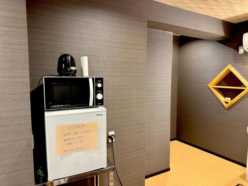 a room with a microwave on top of a refrigerator at ONE HOSTEL Himeji ワンホステル姫路 in Himeji