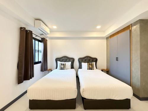 two beds in a room with white walls at Freeda House Bang Tao Beach - Near Muay Thai Gym in Ban Lum Fuang