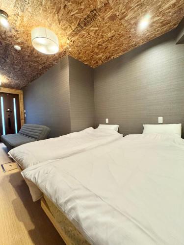 a bedroom with two large white beds in it at ONE HOSTEL Himeji ワンホステル姫路 in Himeji